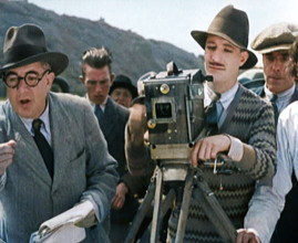 A Male Cameraman Cranking a Camera On a Film Set as the Male Director Instructs Actors, 1920s. Creator: British Pathe Ltd.