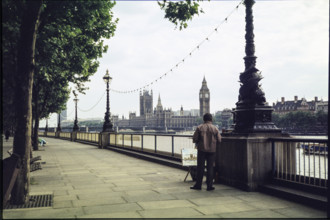 A man on the promenade on the south bank of the Thames near Hungerford Bridge, painting a picture