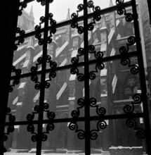Looking through a wrought iron decorative window grille towards the south facade of the nave of