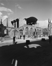 A view of people exploring the ruins of the Cathedral Church of St Michael with the new Coventry