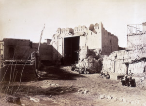 Lahore Gate, Kabul, Afghanistan, c1879. Small groups of people sit along the wall. A dirt track