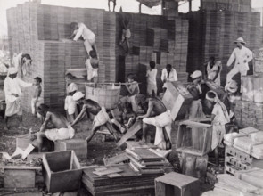 Making tea boxes, Bengal, c1920. Barefoot men and boys assembling crates for packing tea, watched