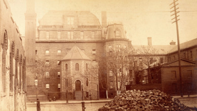 Bellevue Hospital, New York City: hospital buildings with a tower; a pile of bricks in the fore... Creator: Unknown.