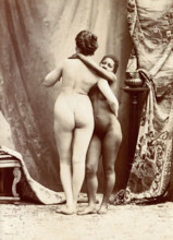 Two women posing naked in a photographic studio, standing embracing each other in front..., c1900. Creator: Unknown.