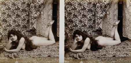 A young woman posing naked in a photographic studio, lying on her front on a piece of..., c1900. Creator: Unknown.