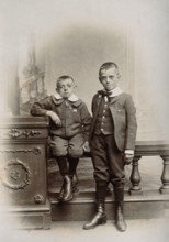Two boys, one sitting and one standing: the former appears physically deformed, 1899. Creator: Unknown.