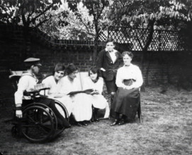 A physically disabled boy sitting in a wheelchair in a garden,  c1910/1925. Creator: Unknown.