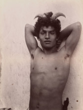 A Sicilian boy naked from the waist up, his hands behind his head, wearing horns, 3 Feb 1899. Creator: Count Wilhelm von Gloeden.