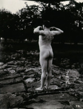 A man posing naked, with his back to the camera, standing on a rocky outcrop, c1900. Creator: Unknown.