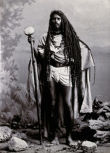 An Indian man with long hair, carrying a staff, in a studio setting, 1900. Creator: Unknown.