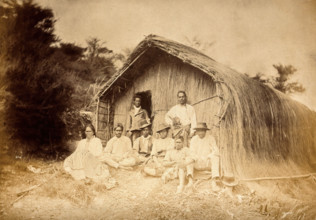 New Zealand: a group of Maori sitting in front of a traditional house, between 1800 and 1899. Creator: Unknown.