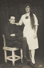 Two prisoners of war, one in drag, pose with a chair, [between 1910 and 1919?]. Creator: Unknown.