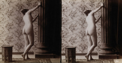 A young woman posing naked in a photographic studio, with her back to the camera looking..., c1900. Creator: Unknown.