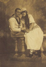 Two sailors, one in drag, embracing while sitting on a stage balcony, (between 1910 and 1919?). Creator: Unknown.