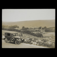 A woman standing beside a car parked on East Dean Road near Exceat Hill, looking out..., 1921-1939. Creator: Norman Kingsley Harrison.