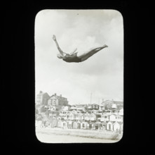 A swimmer diving into the sea at Southcliff, Walton-on-the-Naze, with beach huts on South..., 1920s. Creator: Norman Kingsley Harrison.