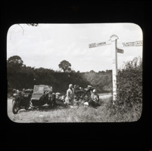 A group of people with two motorcycles and a sidecar having a picnic at the side of..., 1926-1939.  Creator: Norman Kingsley Harrison.