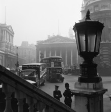 View past a lamp showing the busy traffic outside The Bank of England..., London, probably 1960s. Creator: John Gay.