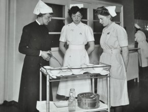 A Sister imparts knowledge and technical expertise to two trainee nurses, c1950s. Creator: Unknown.