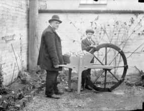 A man holding his potato planting invention, an adapted cartwheel with pockets..., England, 1900. Creator: Henry Taunt.
