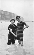 En 1908 à Etretat, couple prenant un bain de mer devant les falaises.