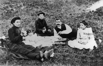 Vers 1900-1910, une famille pique-nique sur l'herbe.