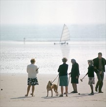 Dans les années 1970, sur une plage normande, des vacanciers jouent au croquet en regardant passer