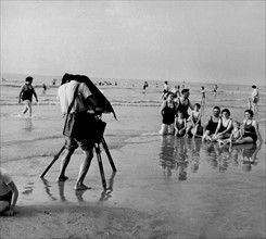 Eté 1951, sur la plage de Deauville, un photographe de plage prend en photo un groupes de baigneurs