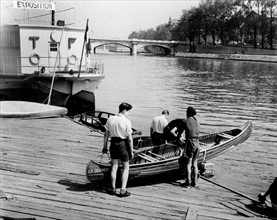 En juin 1950, à Paris, sur les bords de Seine, dans le port de plaisance, deux adolescents mettent