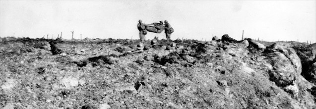 Sur le chemin des Dames : un officier blessé est emporté sur un brancard on voit à ras de terre,