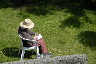 Elderly woman making a drawing in a garden