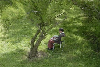 Elderly woman making a drawing in a garden