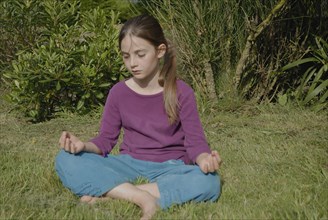 9 year-old child making yoga in a garden