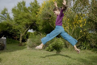 Petite fille faisant un grand saut dans un jardin