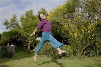 Petite fille faisant un grand saut dans un jardin