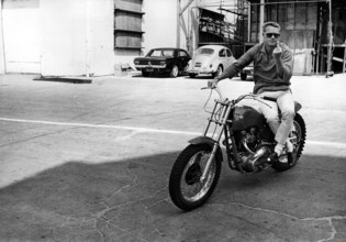 Steve McQUEEN sitting on motorcycle