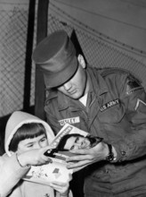 Elvis PRESLEY gives an autograph to a child in 1959