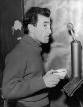 Charles AZNAVOUR with cup in front of microphone and music stand, ca. 1950s