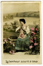 Carte postale représentant une femme posant parmi des fleurs