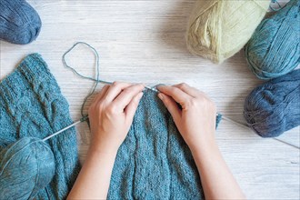 Woman's hands knitting the blue scarf