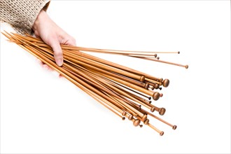 Brown wooden knitting needles in woman hand on white background. Top view
