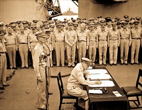 Gen. Douglas MacArthur signs as Supreme Allied Commander during formal surrender ceremonies on the USS MISSOURI in Tokyo Bay.  Behind Gen. MacArthur are Lt. Gen. Jonathan Wainwright and Lt. Gen. A. E....