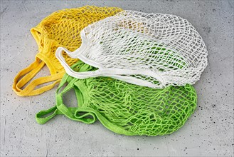 Three eco cotton string bag on a concrete background