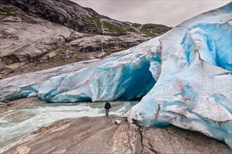 Jostedalsbreen glacier with the glacial river and man in Norway - melting because of Global warming.