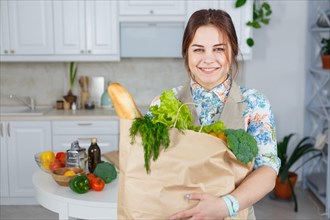 Young woman in the kitchen with a bag of groceries shopping