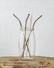 Three reusable metal drinking straws and cleaning brush in a jar over grey background. Zero Waste and minimalism lifestyle