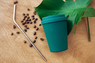 Zero waste concept. Stylish reusable eco coffee cup and metallic steel straws on wooden background with green monstera leaf. Ban single use plastic. S