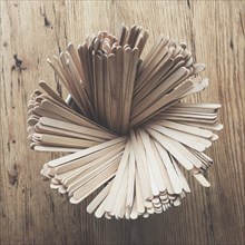 Wooden drink stirrers in a pot on a wooden table