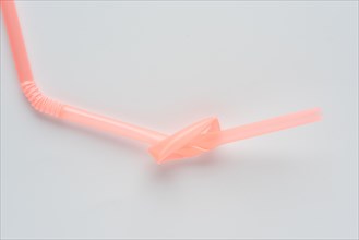 Disposable plastic knotted drinking straw. Conceptual photo about environmental issues.