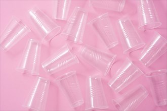 Disposable waste plastic glasses on pink background. Top view